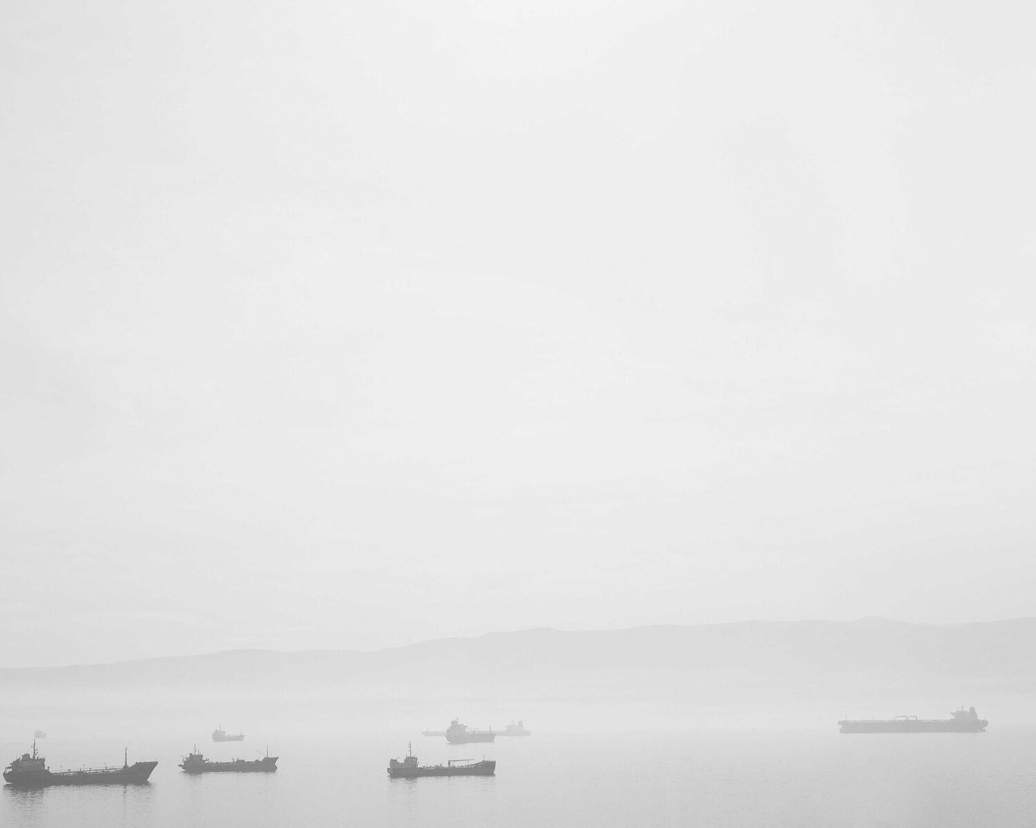 Small boats on a hazy, almost white sea