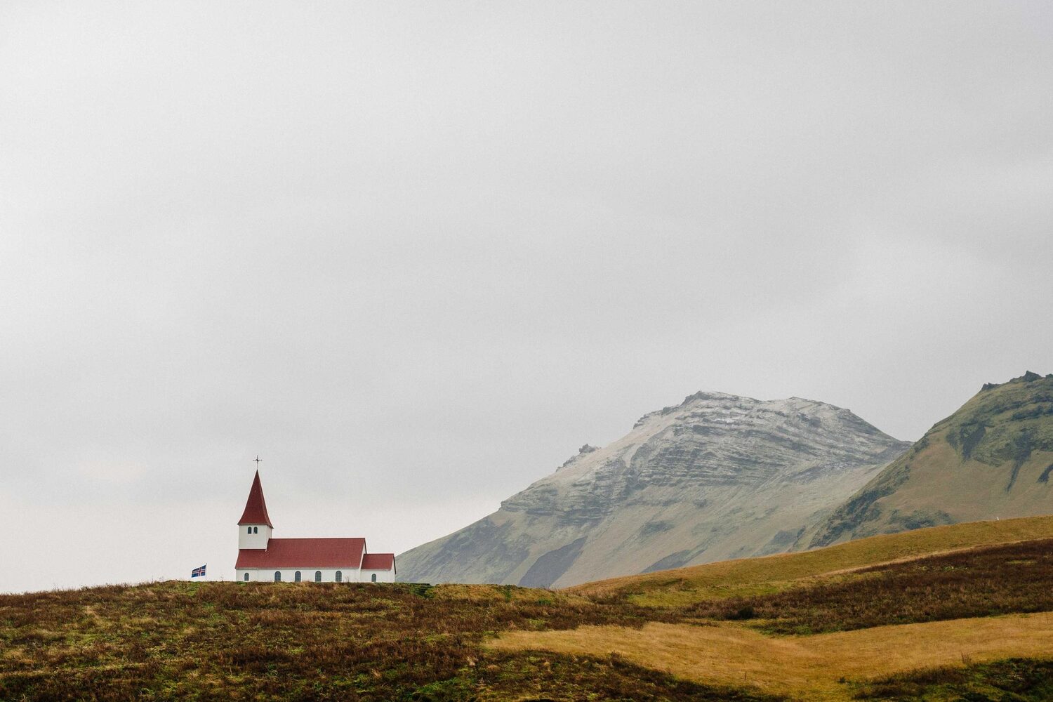Small red church below bare green hills